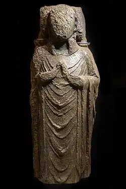 A coffin lid with a carving of a defaced priest lying down.