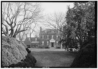 black and white photo of a two and a half-story brick colonial home with wing on left