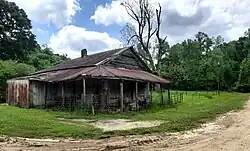 unpainted, wooden store, with tin roof, and single rusting gas pump
