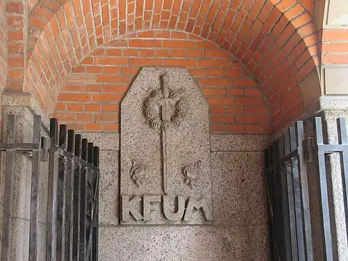 Relief above the basement entrance in the arcade.