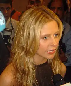 Sarah Michelle Gellar speaking into a microphone in a dark sleeveless top