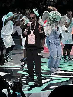 The rapper Slick Rick performs at a basketball arena with backup dancers and the team mascot for the NY Liberty