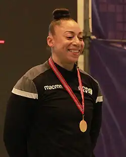 Koanda smiling and wearing a gold medal draped around her neck