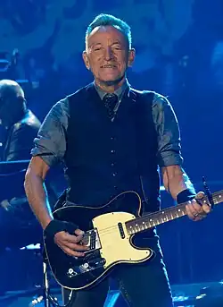 A man performing the guitar on stage