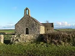 A stone very simple church see from the west end. The only features are a small round-headed door, a small bellcote, and a tiny rectangular window