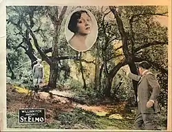 Two men in a wooded area, one with gun raised