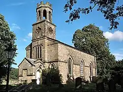 A single storey small church, constructed of sandstone, surrounded by trees