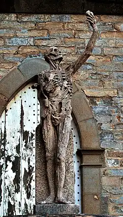 Replica of the skeleton before a stone wall and domed window