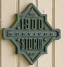 A building with a plaque reading "1900 Storm Survivor", with the year 2000 at the top and 1900 again at the bottom