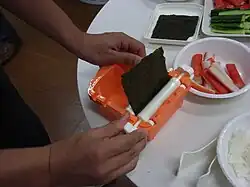 Nori being wrapped around the roll