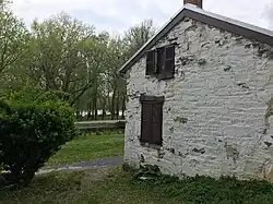 side of old white building with woods and river in background