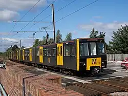 Yellow passenger train next to a stone wall