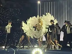 Swift onstage surrounded by backup dancers holding feathers
