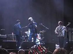 Several men performing onstage playing and singing into a microphone