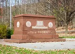 A brick tomb of Jim Thorpe inscribed with depictions of his career and the quote from King Gustav V