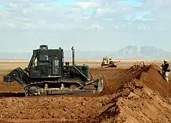 Armored bulldozers erect the protective perimeter of a forward operating base (Helmand, Afghanistan, 2009)