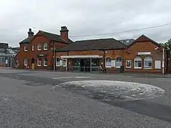 Modernised Victorian railway station with a bus turning circle in front. The station building has gable roof and arched windows.