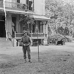Men standing in front of building next to a small flag pole