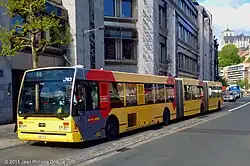 A long, yellow, bi-articulated bus viewed from its left-front corner.