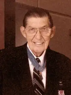 Color photo of Barfoot wearing his Medal of Honor and a blue suit. He is facing the camera and smiling.