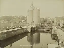 The lock with 'het landje van top' on the left and the Drommedaris around 1870. The wide bridge and the house next to the bridge with tilted covered balconies are still present on this photo. It is the oldest picture of the Drommedaris.