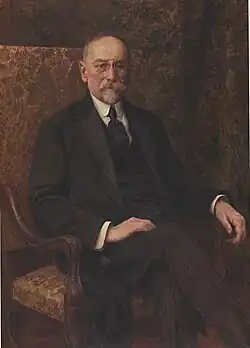 An impressionist painting of an old balding man with a large goatee sitting in an ornate chair wearing a suit and pince-nez