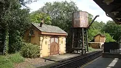 A water tower and two storage buildings adjacent to railroad track