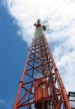 A view from the base of a very tall red-and-white guyed lattice tower