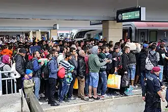 A photograph of a group of refugees standing on a train station platform