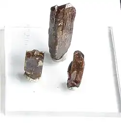 Three column shaped brown crystals on a white background