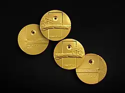 Four gold-coloured medals, two showing obverse, two reverse, dated 2017. The layout of the medal for "Education Development" is mirrored for the "Education research" medal. On the former a person stands looking at a pine tree. On the latter, they sit beneath it.