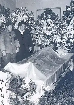 Zhou's wife and daughter stand next to his body during his funeral (1964)