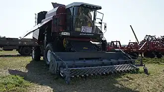 Vooraanzicht van een rode maaidorser met een zwarte opraper als voorzetstuk.