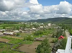 Houten huisjes langs de straten Oekoelanskaja en Ostrovskogo gezien vanaf de spoorbrug over de Aldan