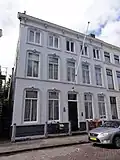 Huis met gebosseerd gepleisterde lijstgevel uit plm. 1870 vensters met kuiven in stuc en afgeronde bovenhoeken