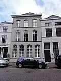 Huis onder hoog schilddak en met gepleisterde lijstgevel, waarin stucversieringen boven de vensters uit omstreeks 1870