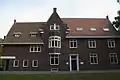 Herenhuis met voormalige personeelswoning gebouwd in de stijl van de Delftse School met expressionistische details zoals die voorkomen in de Amsterdamse School