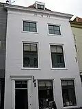 Huis met gepleisterde lijstgevel. Lijst voorzien van tanding en van datering. Moderne 17e-19e-eeuwse winkelpui