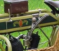 Links van de tank de schakelhefboom en het draaihendel voor de voorontsteking