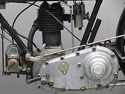 De linkerkant van het blok, met de ontstekingsmagneet en het onhandig hoog geplaatste rempedaal. Het buisje achter de framebuis bevat het benzinespuitje. De uitstulping op het distributiedeksel biedt plaats aan de transmissiedemper.