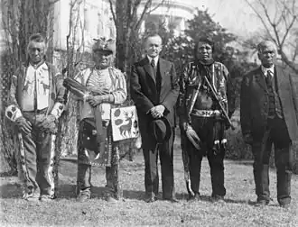 President Calvin Coolidge poseert met enkele Inheemse Amerikanen in de tuin van het Witte Huis na de ondertekening van de Indian Citizenship Act.
