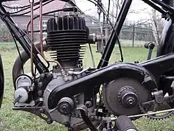 De linkerkant van de motor toont de Lucas-ontstekingsmagneet, de openliggende primaire ketting, het pedaal van de achterrem en het kwadrant van de kickstarter.