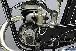 De linkerkant van het motorblok met de carburateur, het inlaatspruitstuk en de ontstekingsmagneet