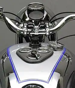 Het instrumentenpaneel met contactschakelaar, lichtschakelaar, ampèremeter en oliedrukmeter. De snelheidsmeter zit op het stuur.