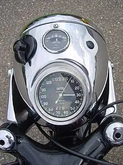 De koplamp met Smith-snelheidsmeter, ampèremeter en lichtschakelaar. De lamp en de lamporen zouden waarschijnlijk nog niet verchroomd moeten zijn.