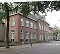 Voormalig kloostergebouw van twee bouwlagen met schilddak, rond 1930 aan de rechterzijde- en in 2000 aan de linkerzijde uitgebreid met een vleugel van twee bouwlagen en een schilddak en aan de achterzijde een kapel uit ca. 1860