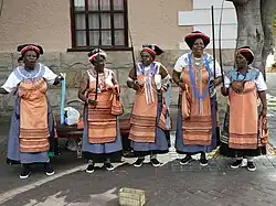 Xhosa-vrouwen in traditionele kledij treden op met indigo shweshwe schorten en beschilderde gezichten. Victoria & Alfred Waterfront, Kaapstad, 2008.