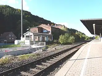 Het eilandperron van Vlotho, kijkend richting Bad Oeynhausen (noorden). Links op de voorgrond de ingang van de voetgangerstunnel, in het midden het oude stationsgebouw, op de achtergrond de Amtshausberg in Vlotho (2013)