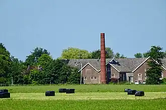 Zicht op de gebouwen en schoorsteen van de voormalige zuivelfabriek De Toekomst in Rinsumageest anno 2020