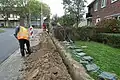 Er wordt een sleuf gegraven in de straat, voor de woningen langs
